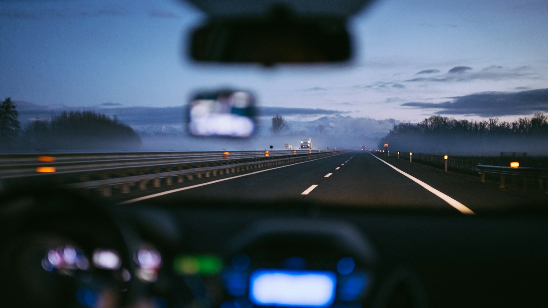 Bestuurdersperspectief op een snelweg tijdens automaat rijden in de schemering met vrij zicht op de weg